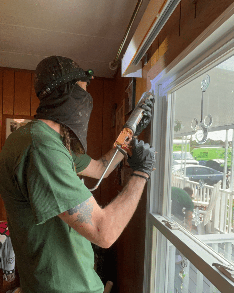 GreenLife employee air Sealing a window