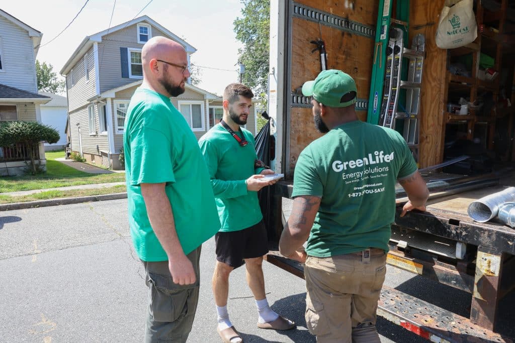 GreenLife Employees talking in fromnt of the company's truck after completing a weatherization job.